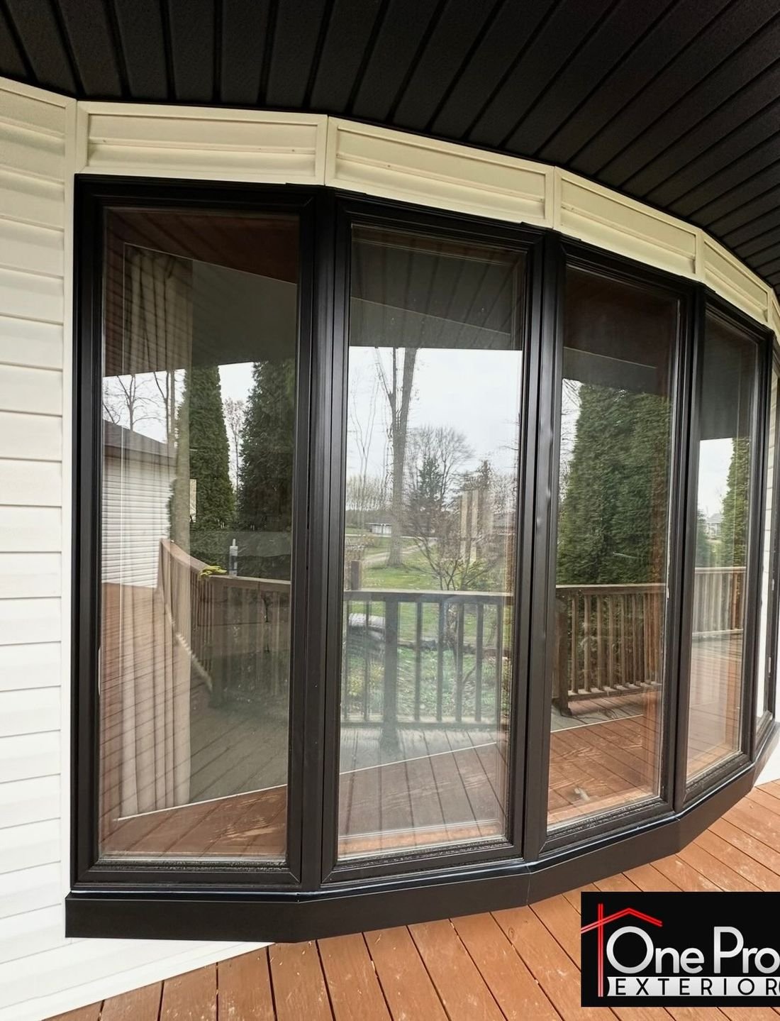 Black bay window installed with black trim wrap under a covered porch