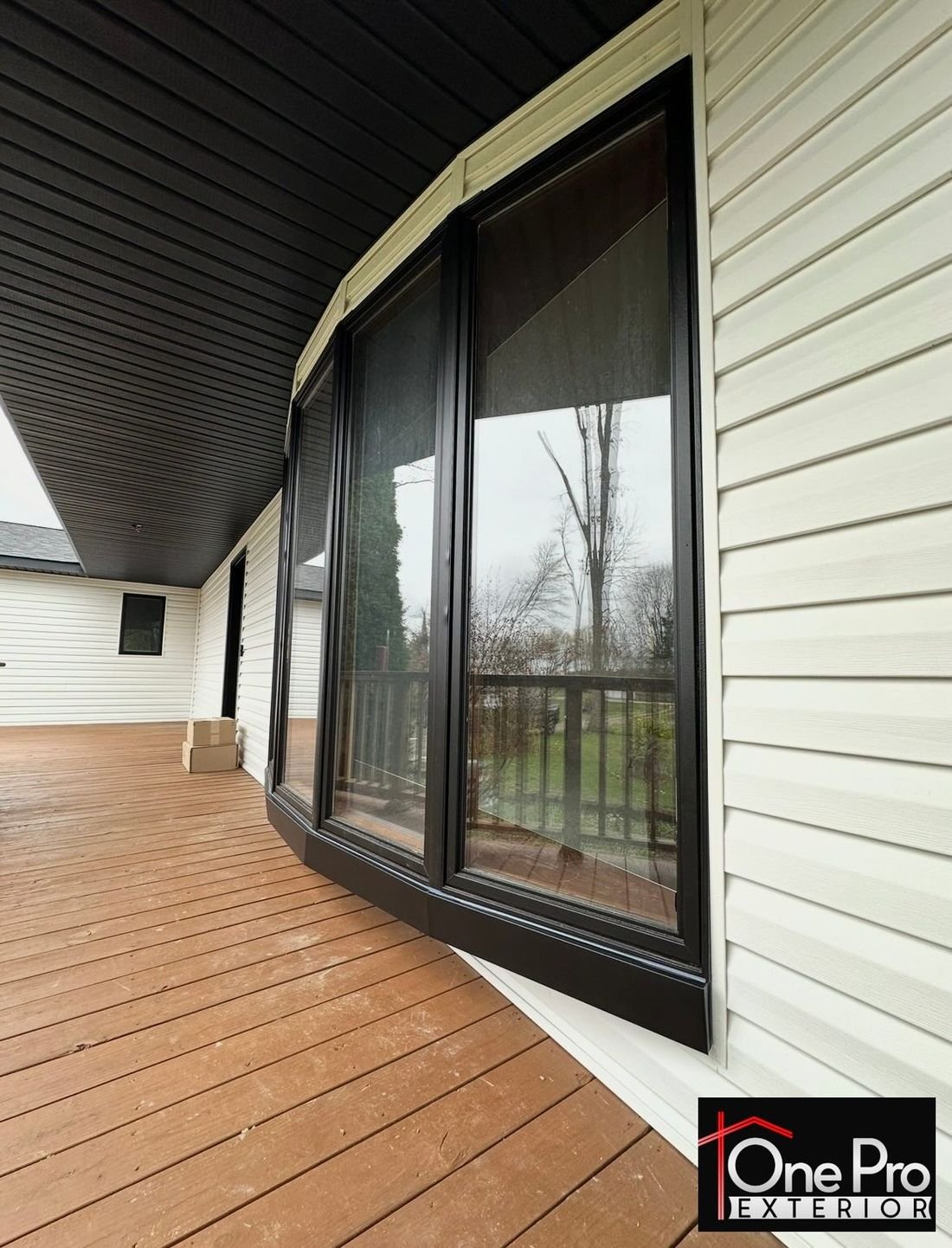 Side view of a black bay window with matching trim along a wood deck